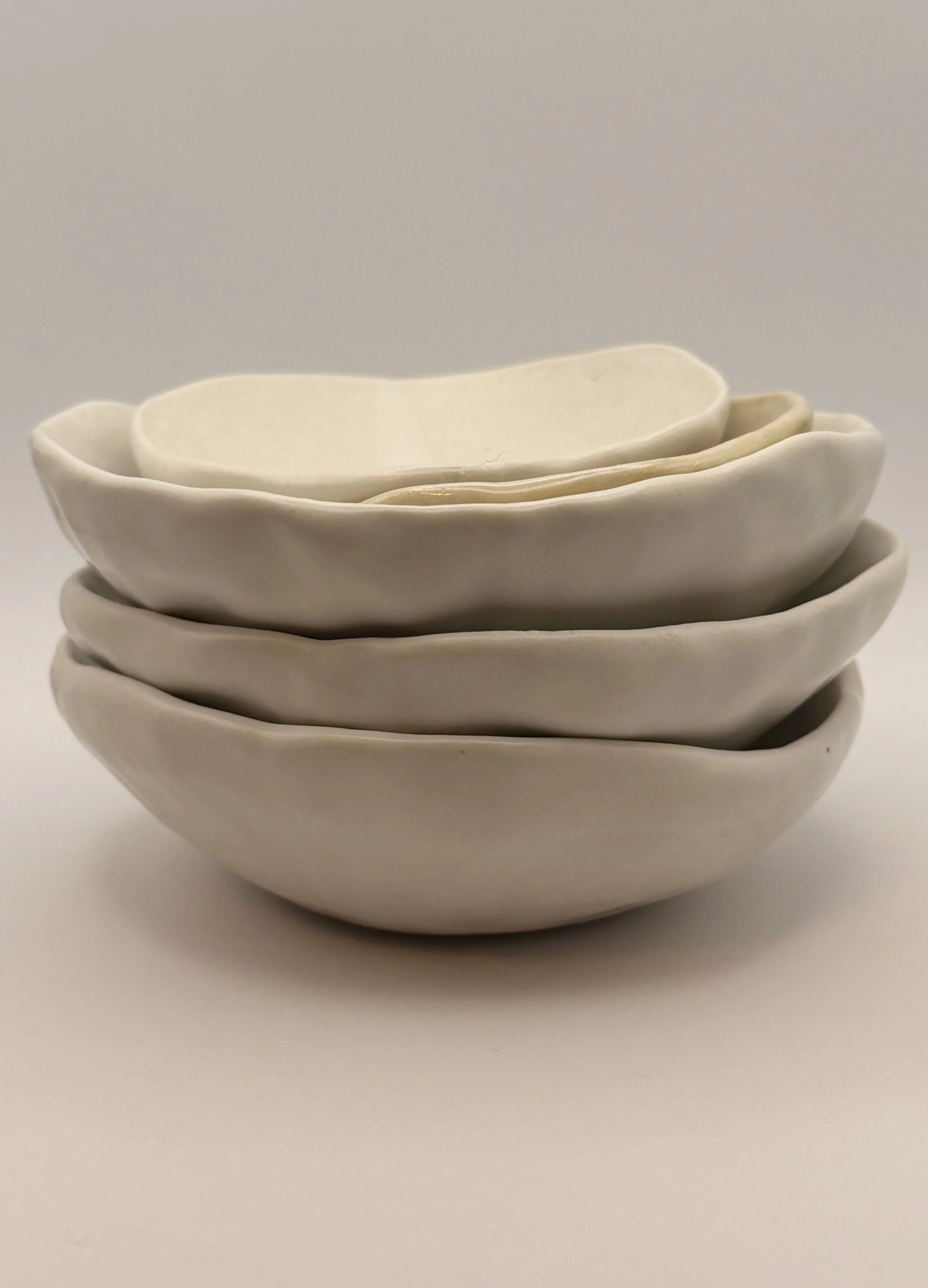 Stacked white ceramic bowls with a slightly wavy rim, set against a plain background.