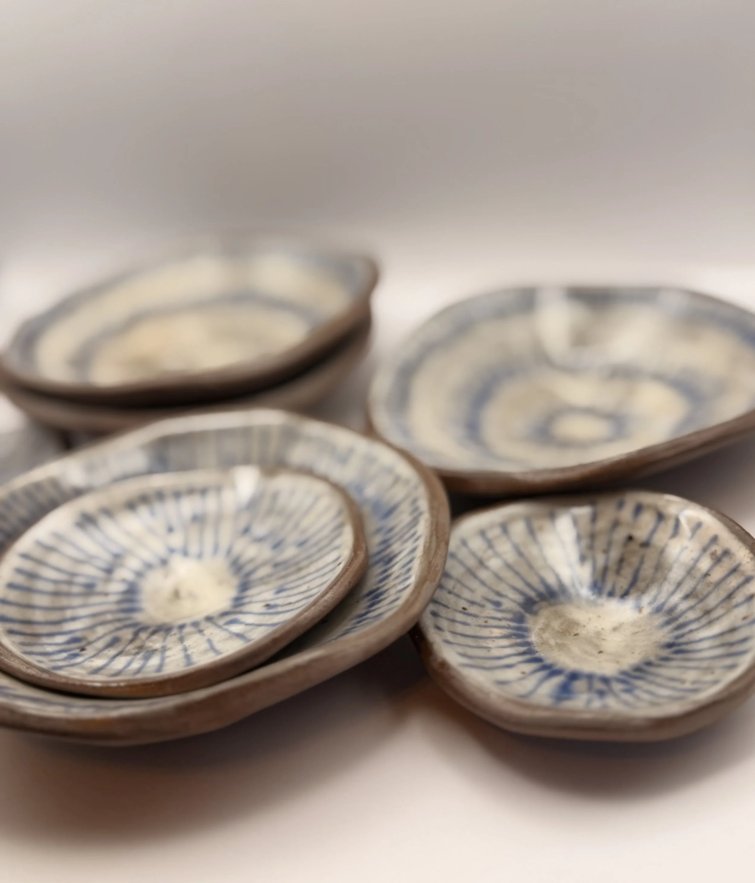 Close-up of several traditional decorative ceramic bowls with blue patterns on white backgrounds, stacked on a white surface.
