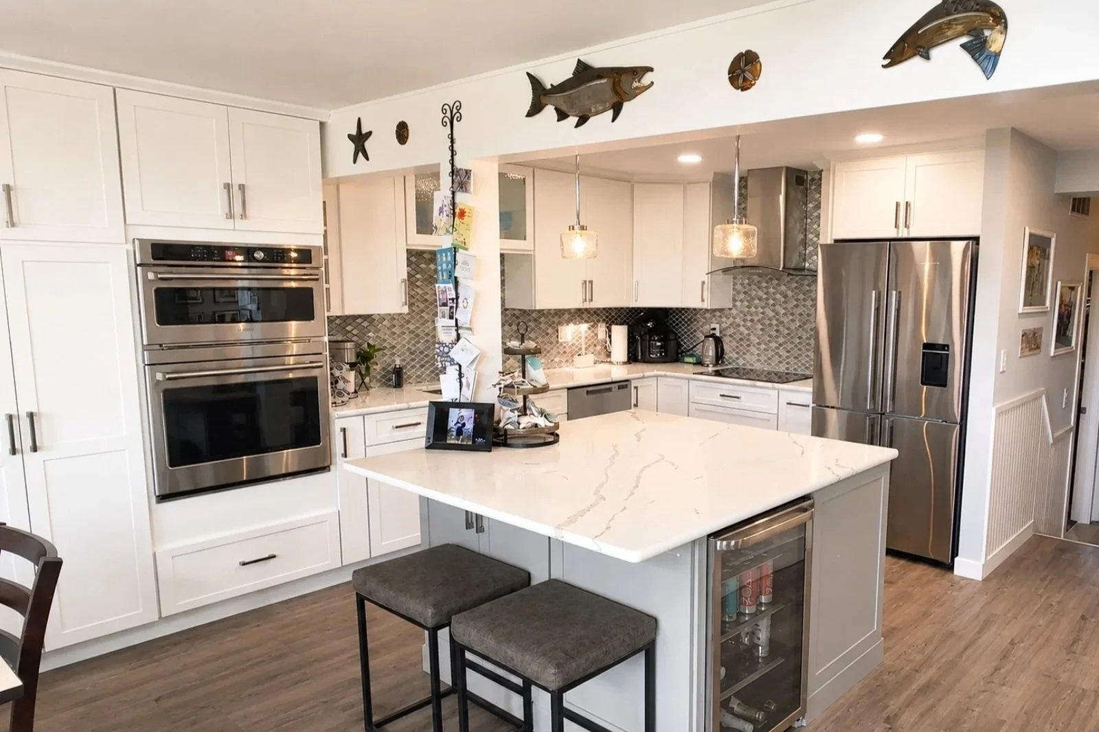 Modern kitchen with white cabinets, stainless steel appliances, a white marble kitchen island, and decorative fish wall art.