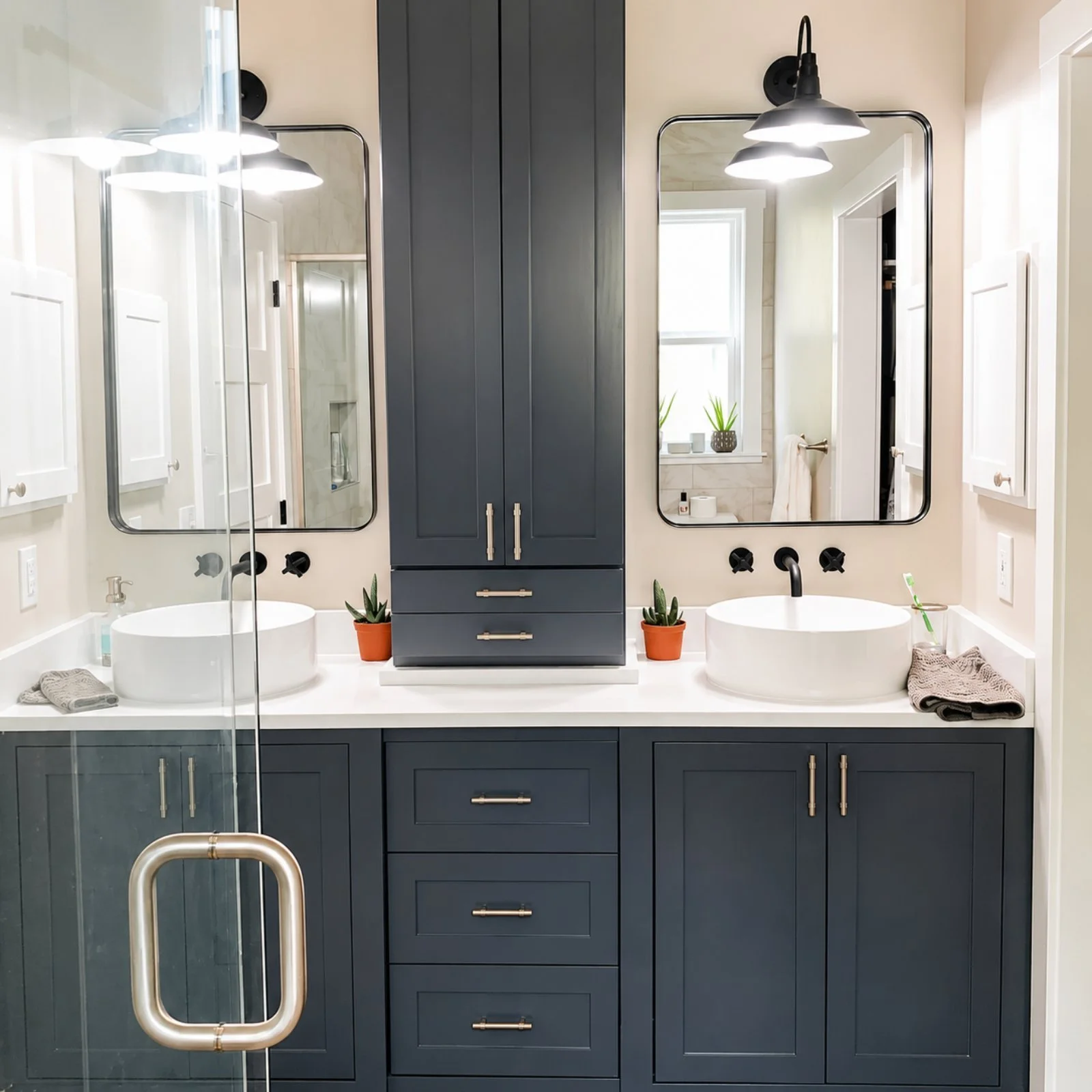 Modern bathroom with double vanity, dark blue cabinets, white countertops, two round vessel sinks, large mirrors, black wall-mounted light fixtures, privacy window with plants, and glass shower door.