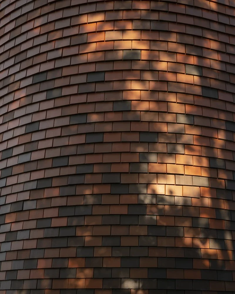 Facade view with clay shingles in dappled light.