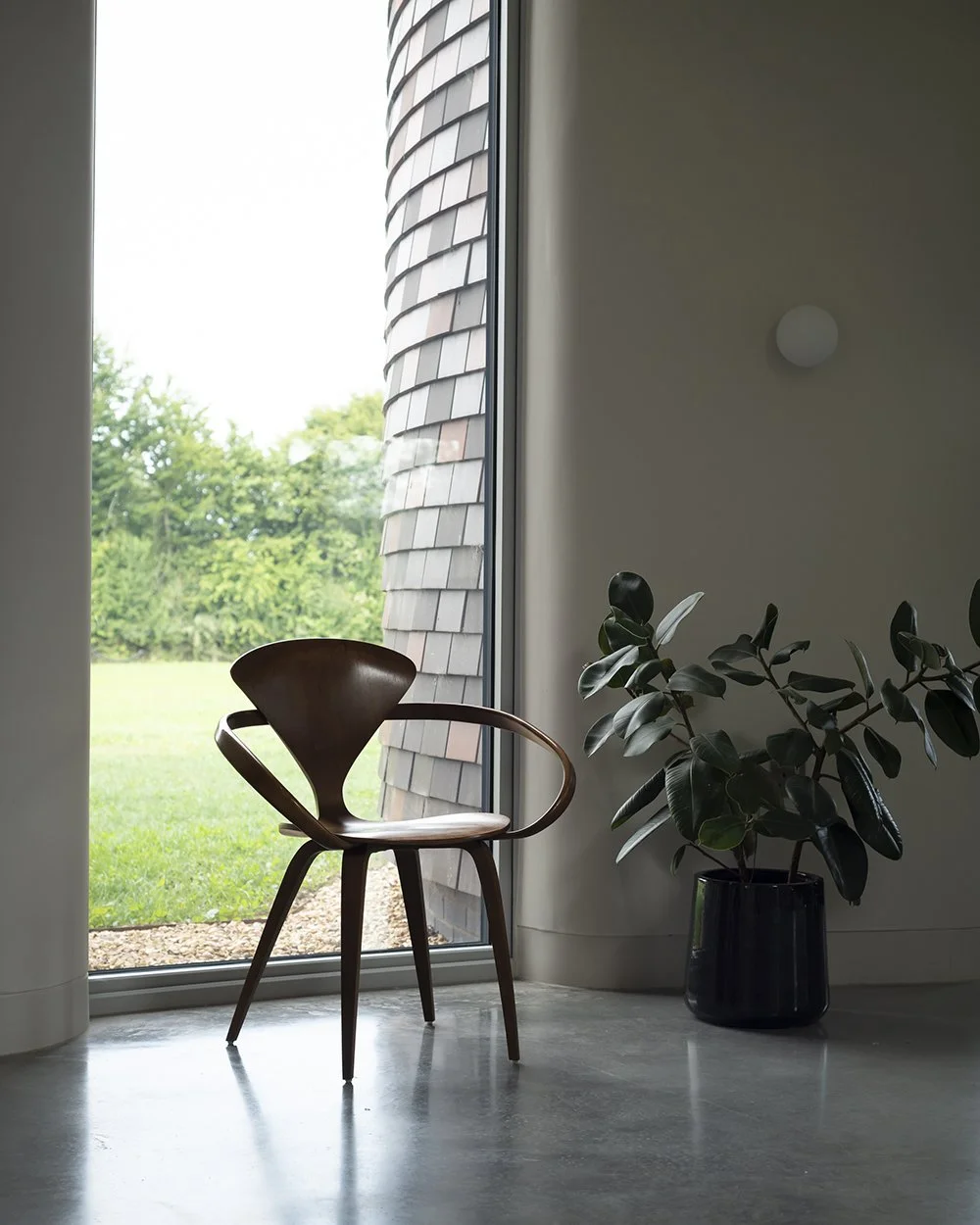Bumpers Oast, Lucy Moroney Project Architect, Minimal interior view polished concrete, large atrium windows with 1958 moulded plywood armchair by Norman Cherner
