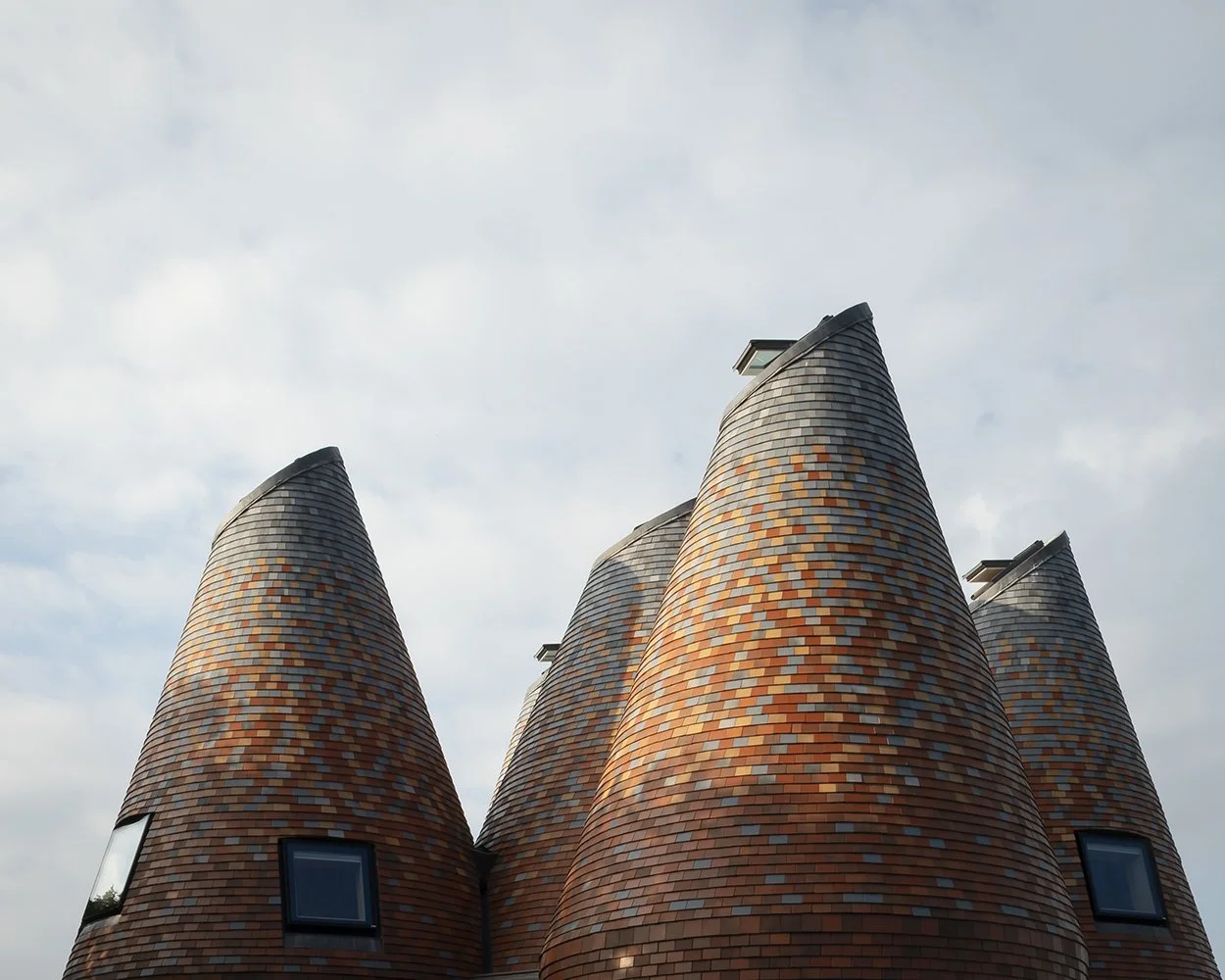 View of the conical forms with earth-toned clay tiles fading to grey-blue tones.