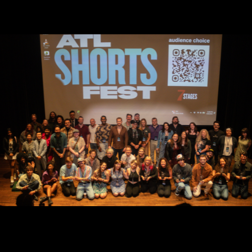 Group of people on stage at ATL Shorts Fest with a large projection screen in the background displaying the event name and a QR code.
