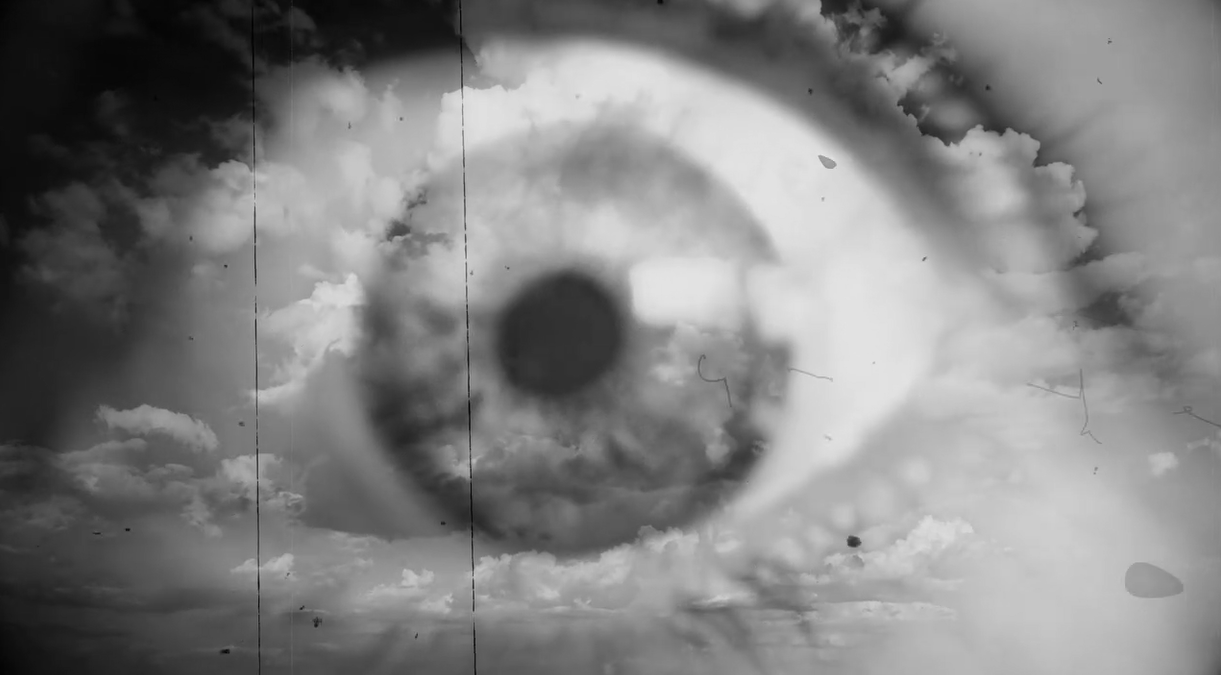 A large eye superimposed over a cloudy sky in a black and white photo.