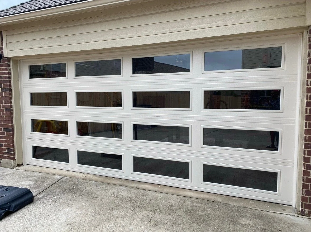 White garage door with rectangular windows and brick sides.