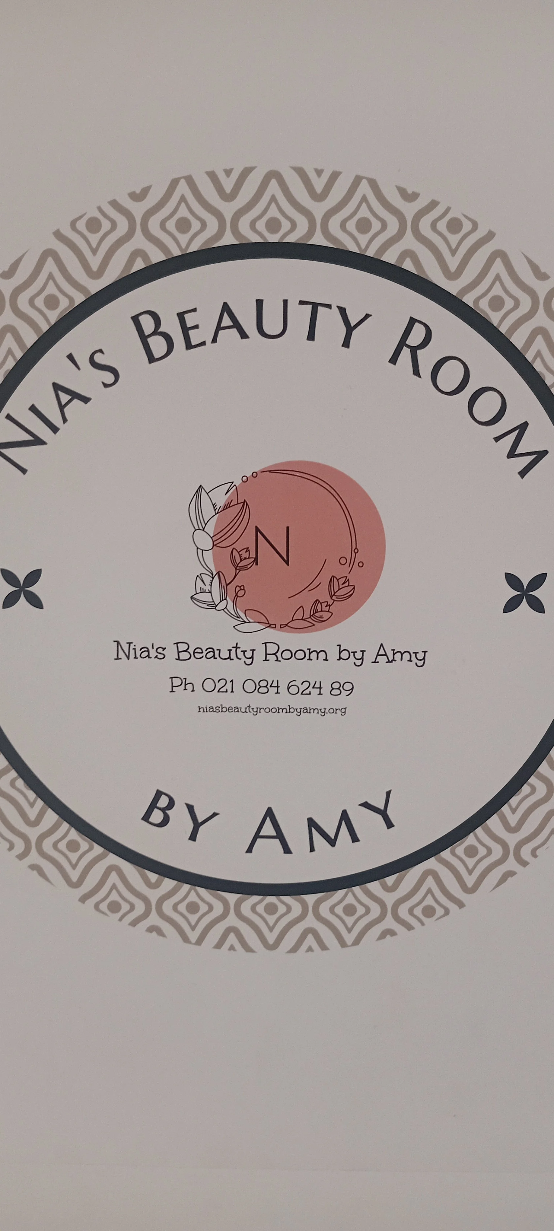 Business card for Nia's Beauty Room by Amy with contact information and a decorative logo featuring a pink circle with a leaf and flower design.
