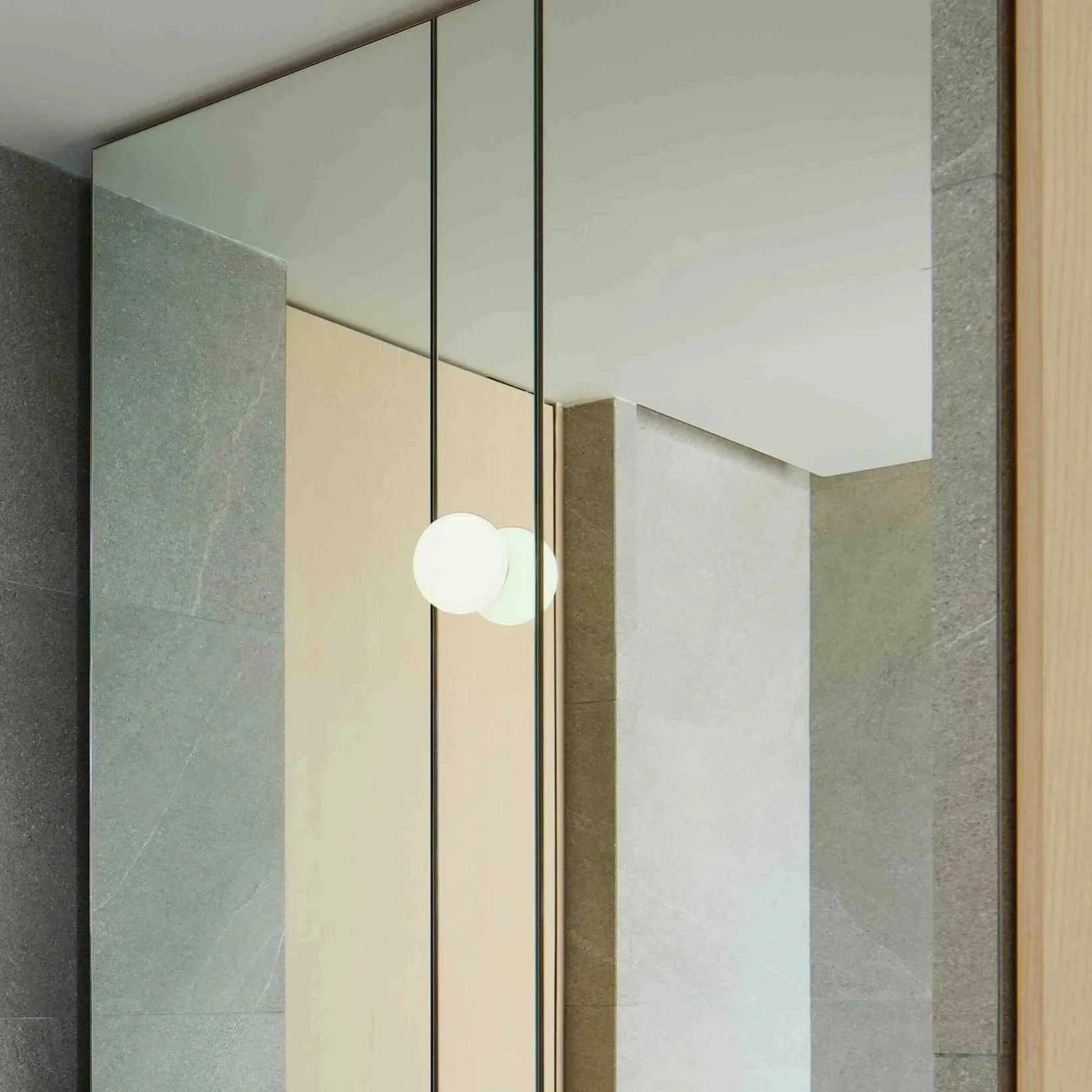 Interior of a modern building with a large mirror, a lamp, drywall, and stone wall panels.