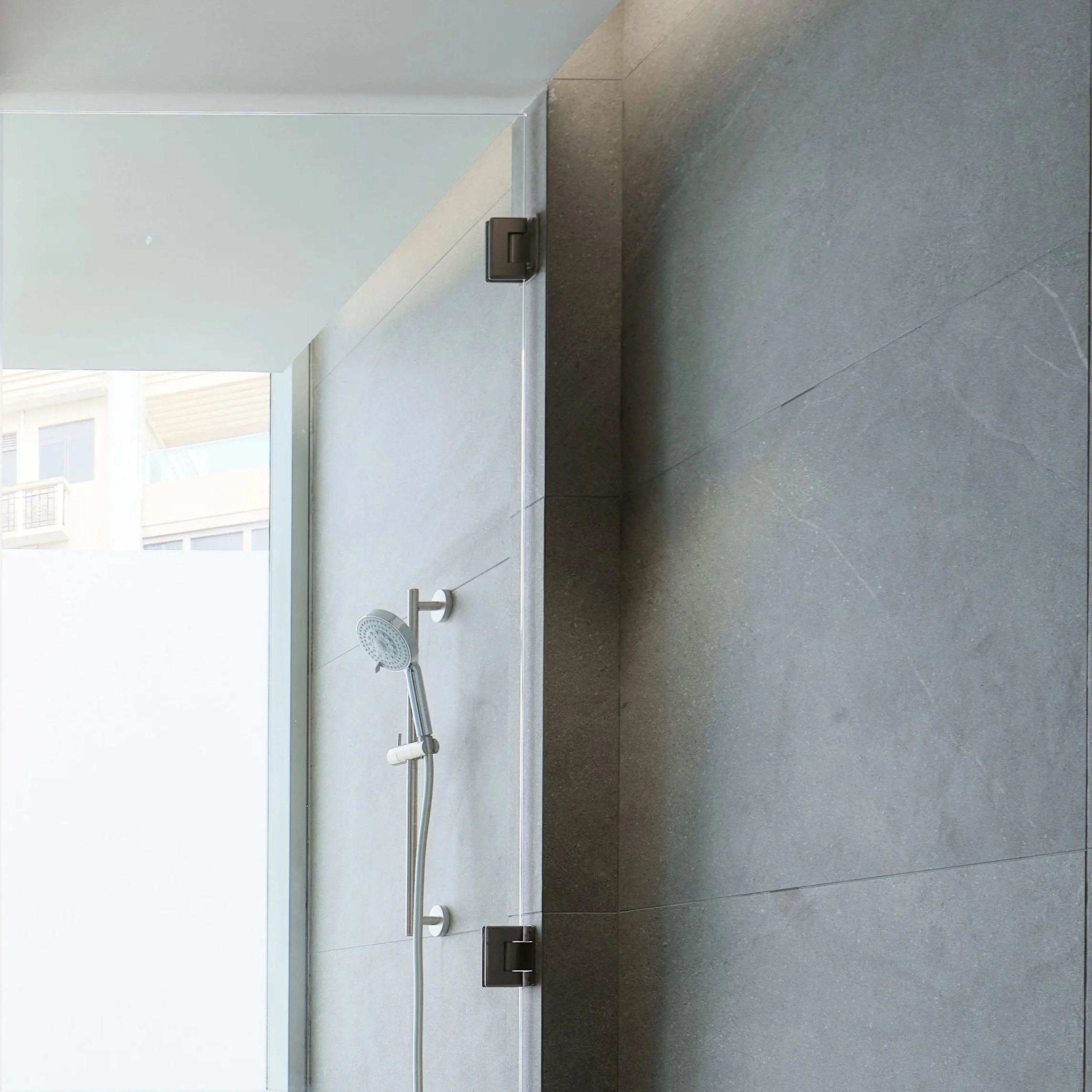 Shower with a handheld showerhead, faucet, and tiled walls and floor.
