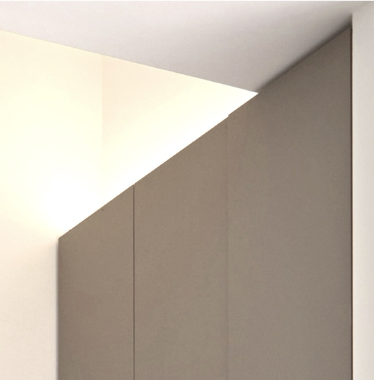 Close-up of a corner in a room with a sloped ceiling, showing beige and white walls.