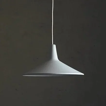 A white pendant lamp hanging from a white cord against a dark wall.