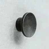 Close-up of a black cylindrical door knob attached to a gray wall.