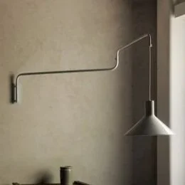 Wall-mounted lamp with a long adjustable arm extending from a wall, with a conical shade.