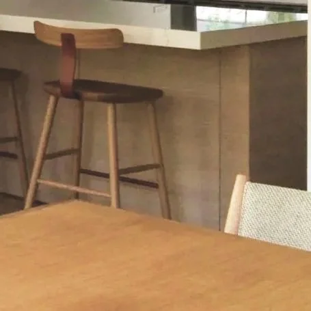 A wooden bar stool with a curved backrest placed at a kitchen island.