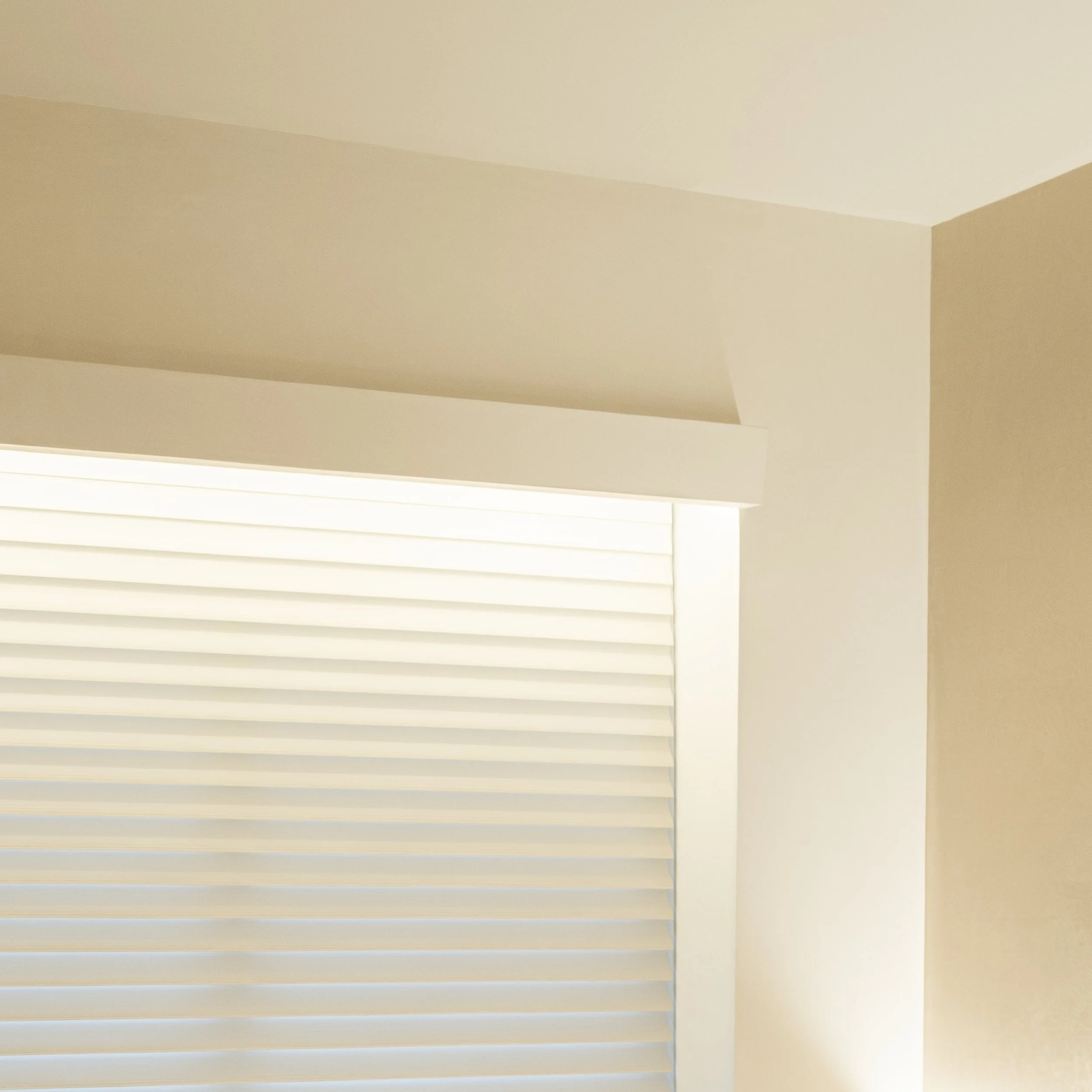 A ceiling with white ceiling tiles and a beige wall corner.