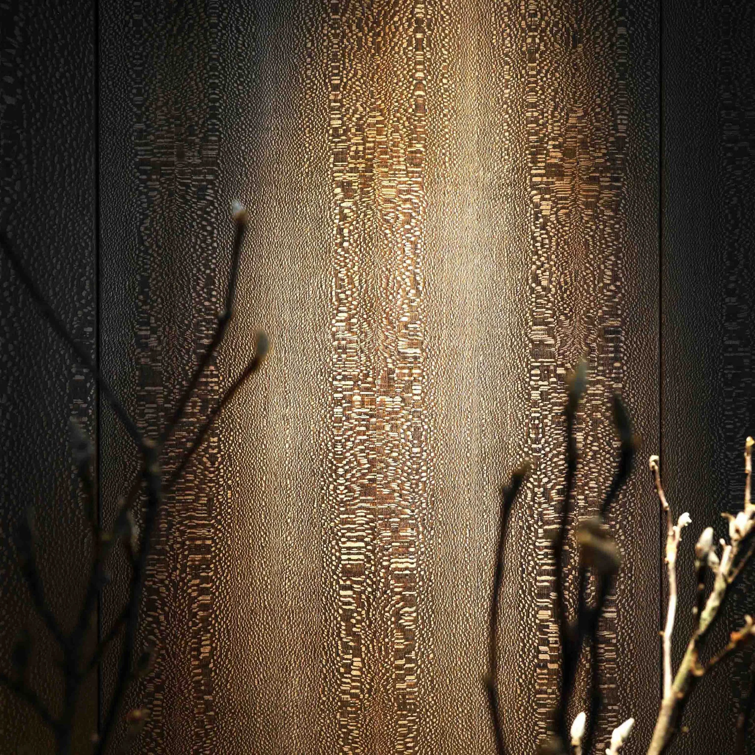Close-up of a decorative gold metal screen with intricate pattern, backlit to create a glowing effect.