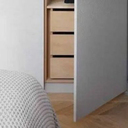 Partially open closet door revealing a wooden dresser with several drawers inside a bedroom.