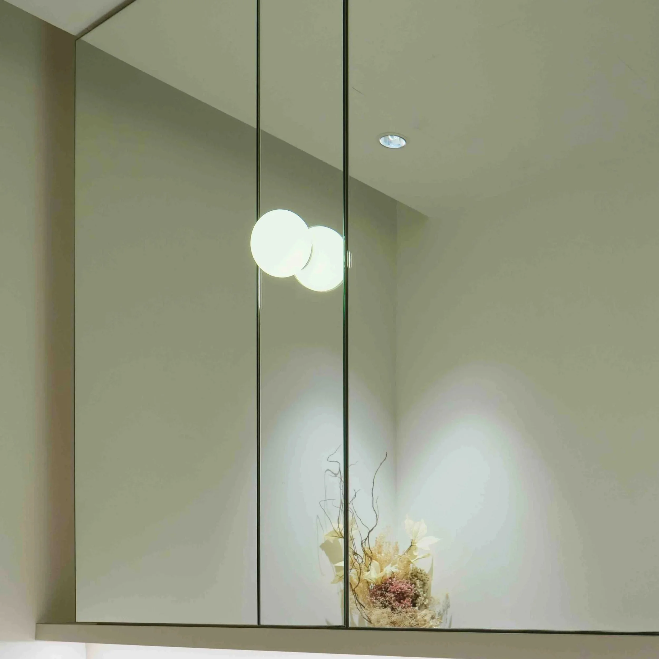 Interior mirror with hanging spherical pendant lights and a floral arrangement at the bottom, reflecting in the mirror.