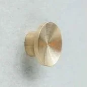 Close-up of a gold-colored, round door knob on a light-colored wall.