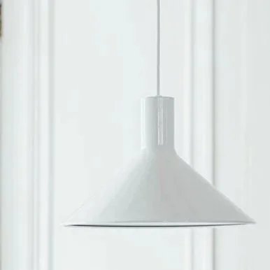 A white pendant light hanging from the ceiling in front of a white wall with vertical paneling.