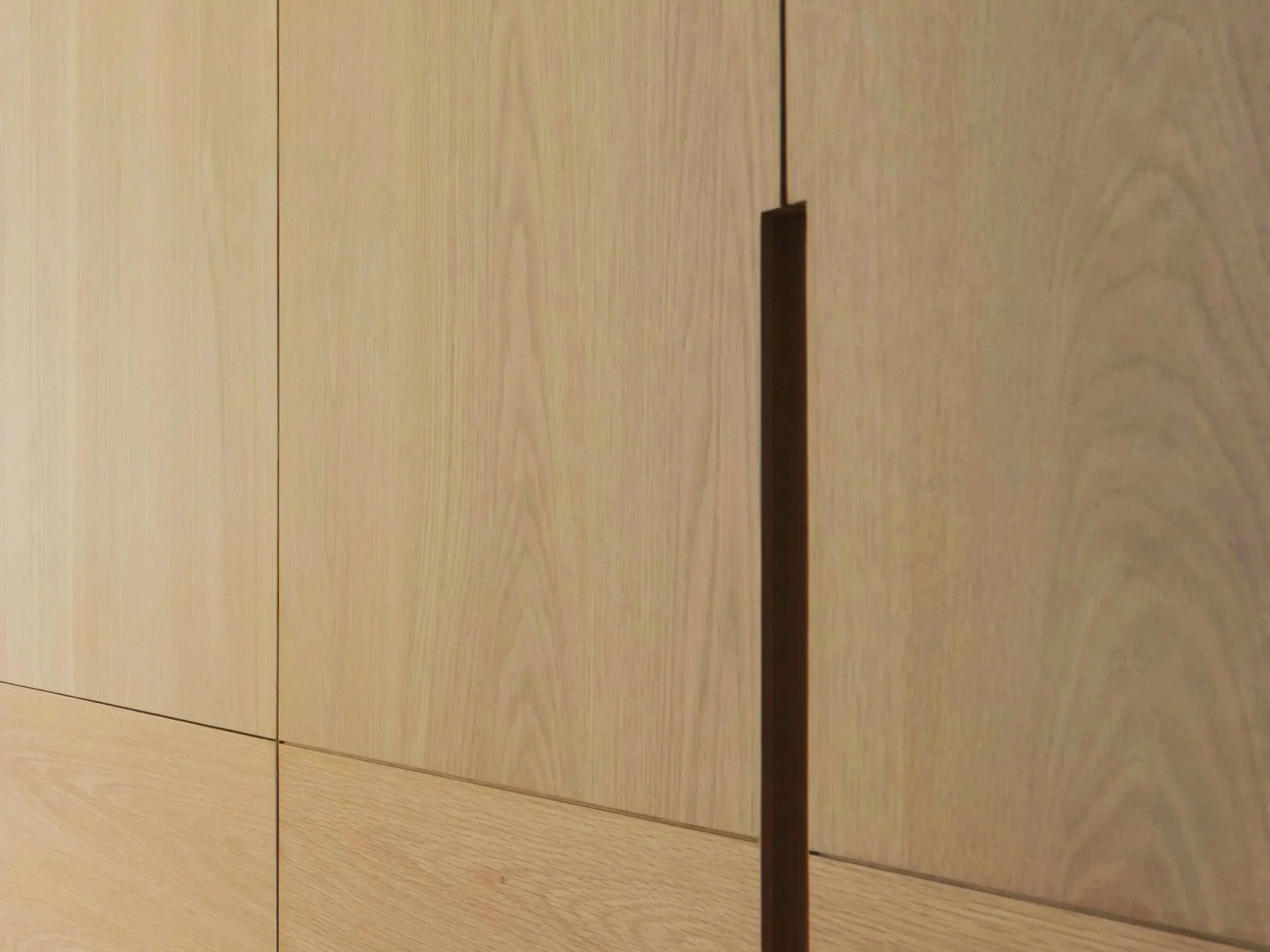Close-up of a light wood surface, possibly a table or floor, with a vertical dark shadow or crack in the center.