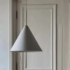 A white pendant lampshade hanging in front of a paneled wall.