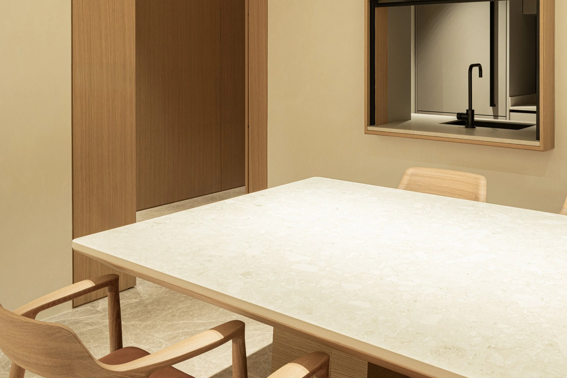 Modern kitchen with a light-colored countertop, black faucet, and wooden accents.