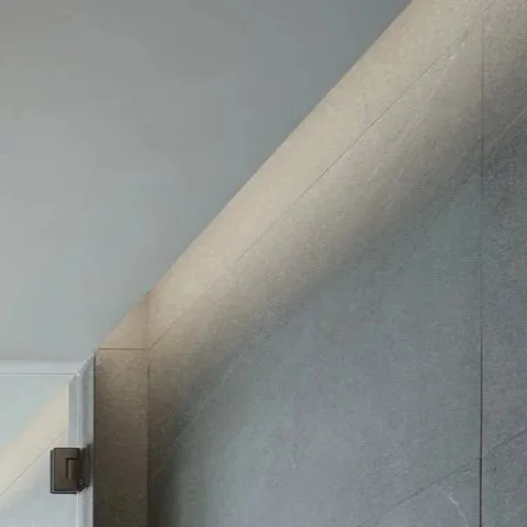Close-up of a textured, gray sloped wall or ceiling with a corner showing a small part of a white ceiling and a metallic object at the edge.