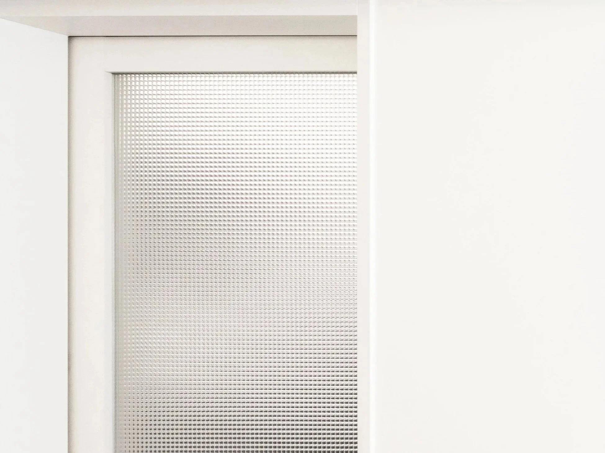 White wall with a rectangular window that has a perforated metallic or plastic panel covering it.