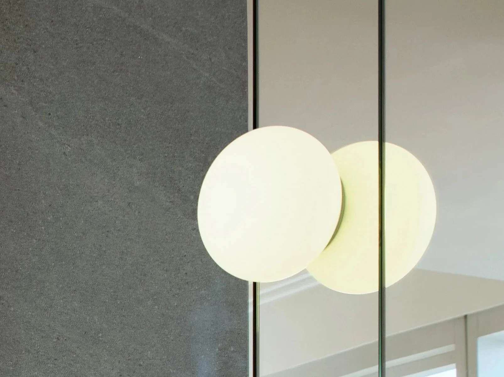 Close-up of modern ceiling lights mounted on a ceiling with gray textured surface, reflected in a mirror.