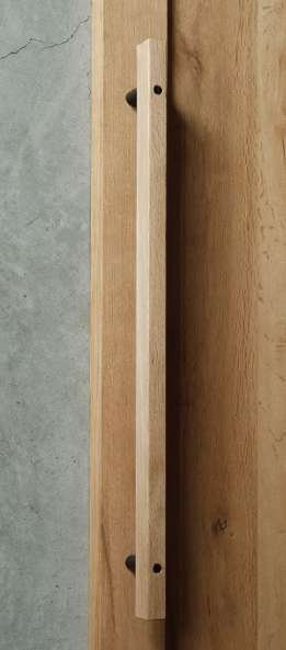 A wooden door latch strip mounted on a wooden door with a concrete wall in the background.