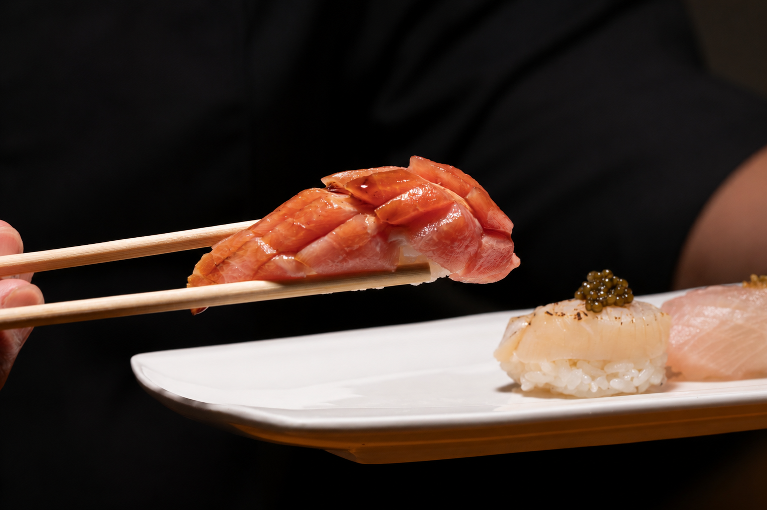 Sushi platter with slices of raw fish, including salmon and yellowtail, served on a white plate.
