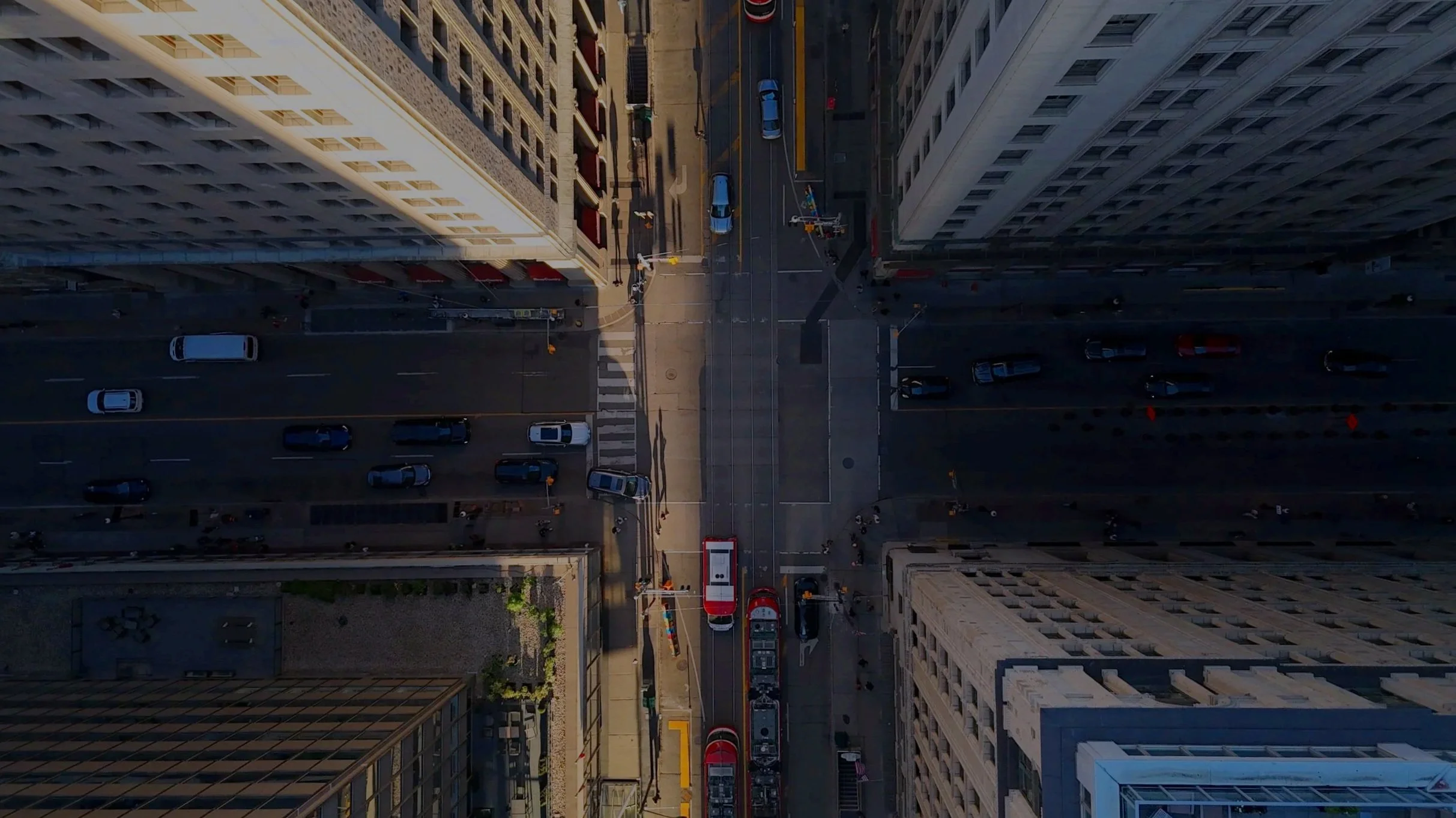 Aerial view of a city street with buildings, parked cars, and a fire truck, taken during daylight hours.