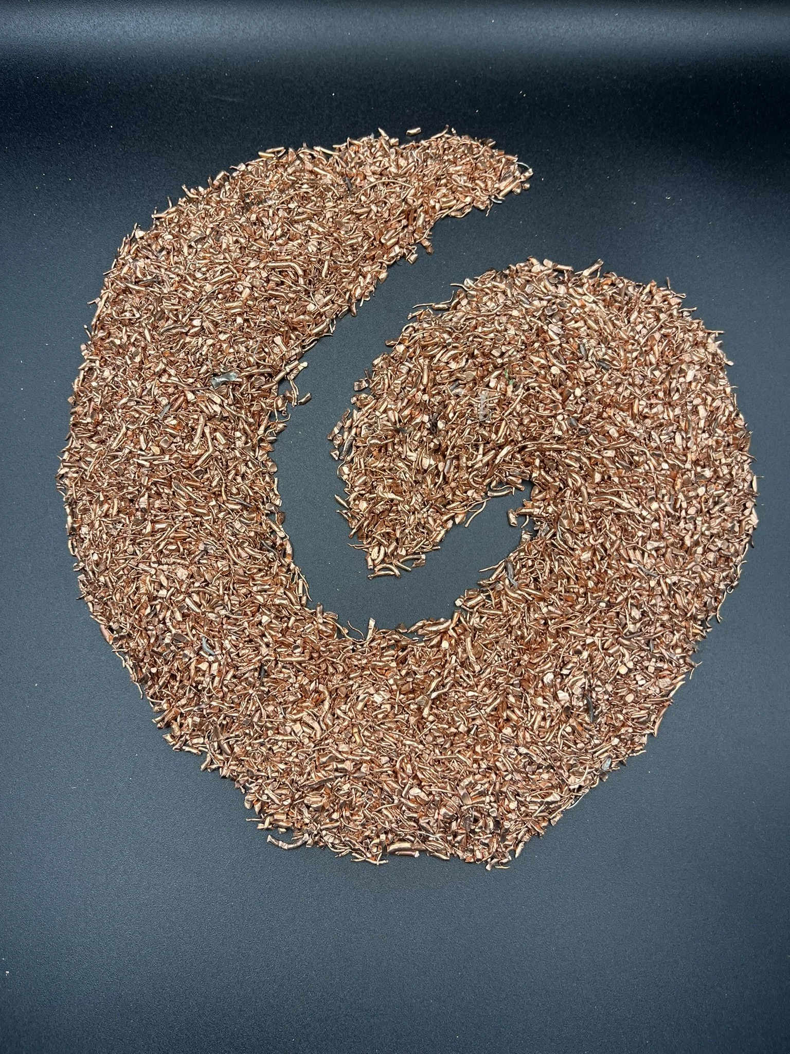 A heart shape made of copper shavings on a dark background.