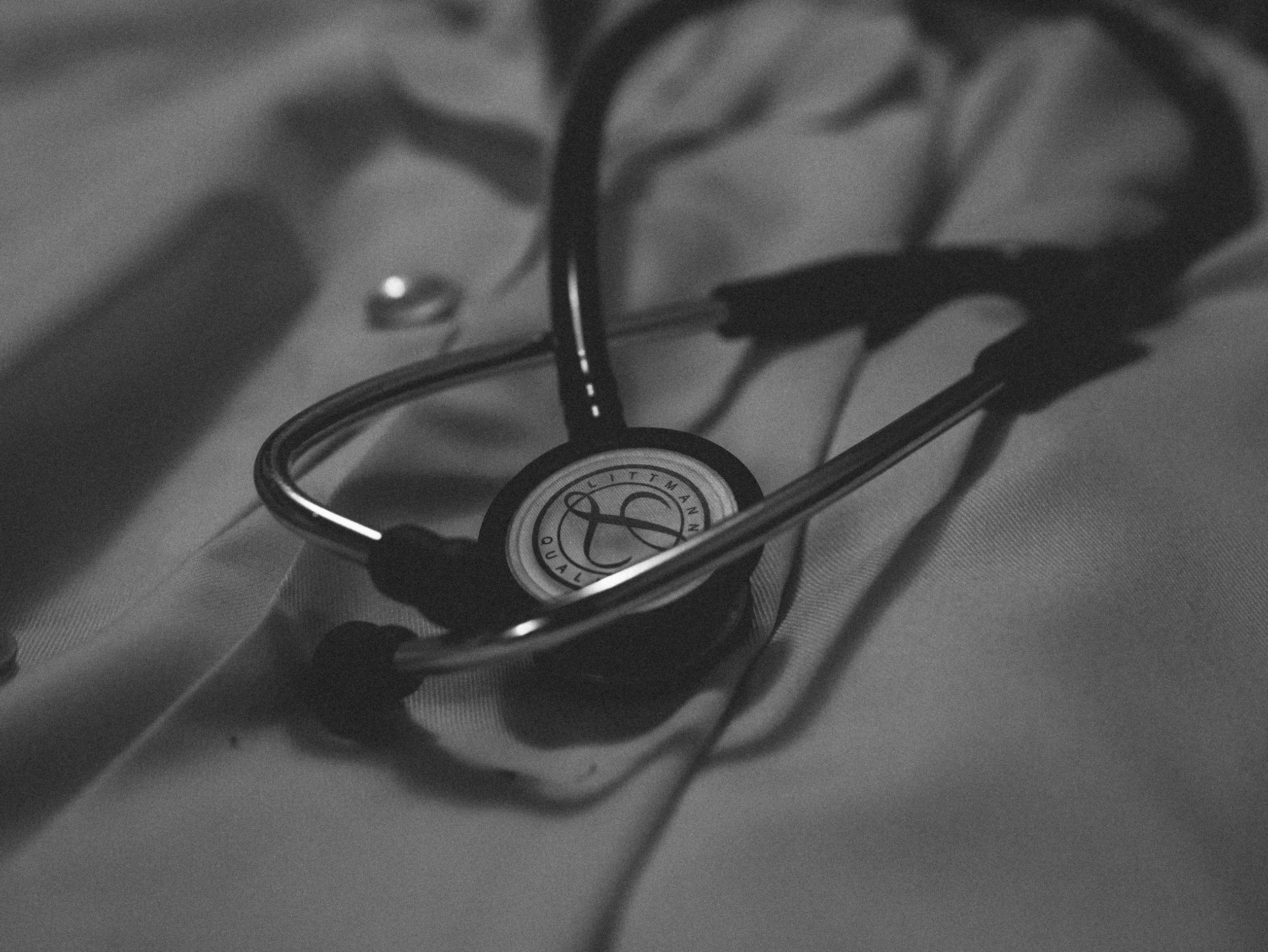 Close-up black and white photo of a metallic item with a circular design and some text, possibly a watch or a badge, on a textured surface.