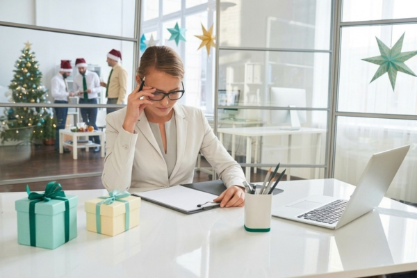 female worker witg glasses sittign at desk looking at cheklist. christmas theme