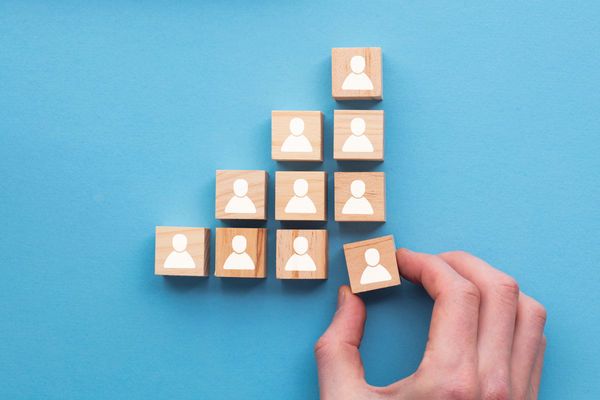 Blocks with people icons positioned on blue background. Hand moving pone block. Managing workplace change.