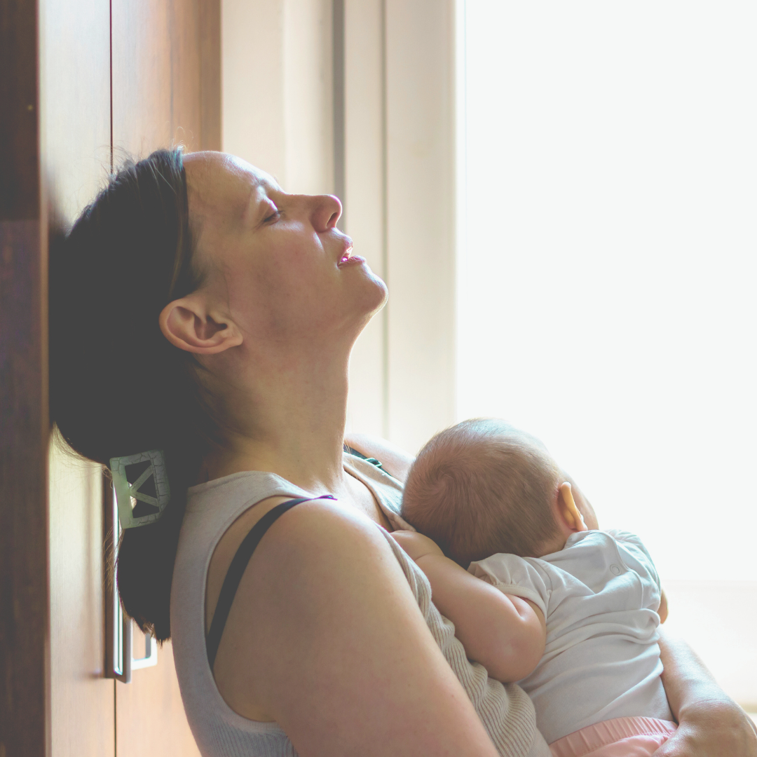 Tired mother holding sleeping baby
