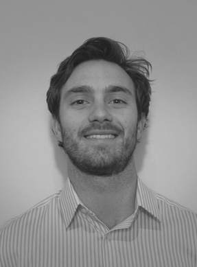 Black and white portrait of a young man with wavy hair and a beard, wearing a striped shirt, smiling slightly.