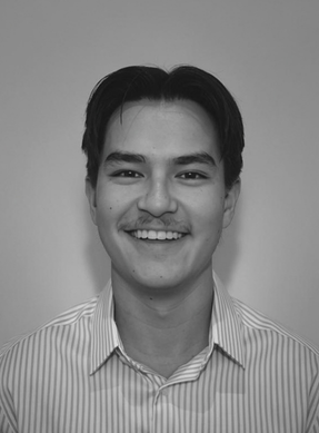 Black and white portrait of a smiling young man with short dark hair, wearing a collared striped shirt.