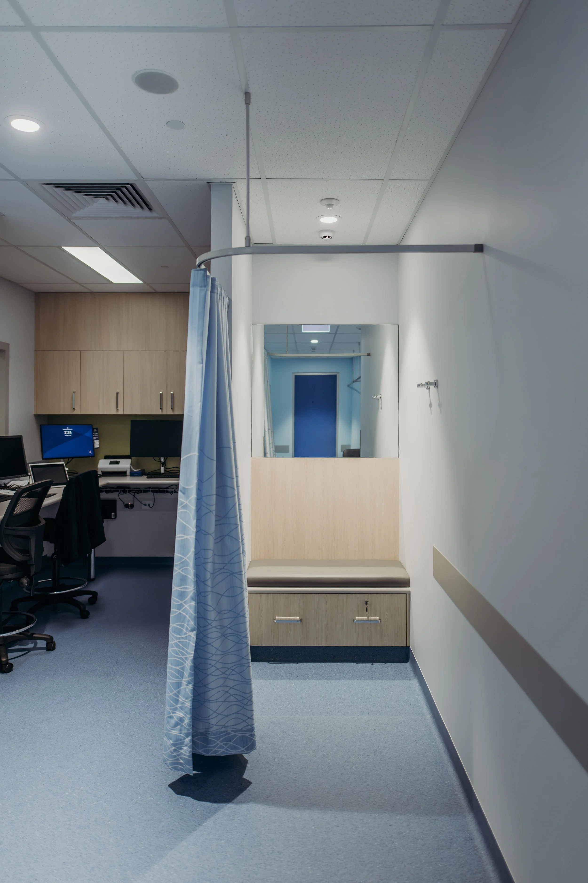 Hospital examination room with curtain, mirror, and seating area