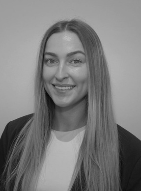 A black-and-white portrait of a young woman with long straight hair, smiling, wearing a blazer and a white shirt.