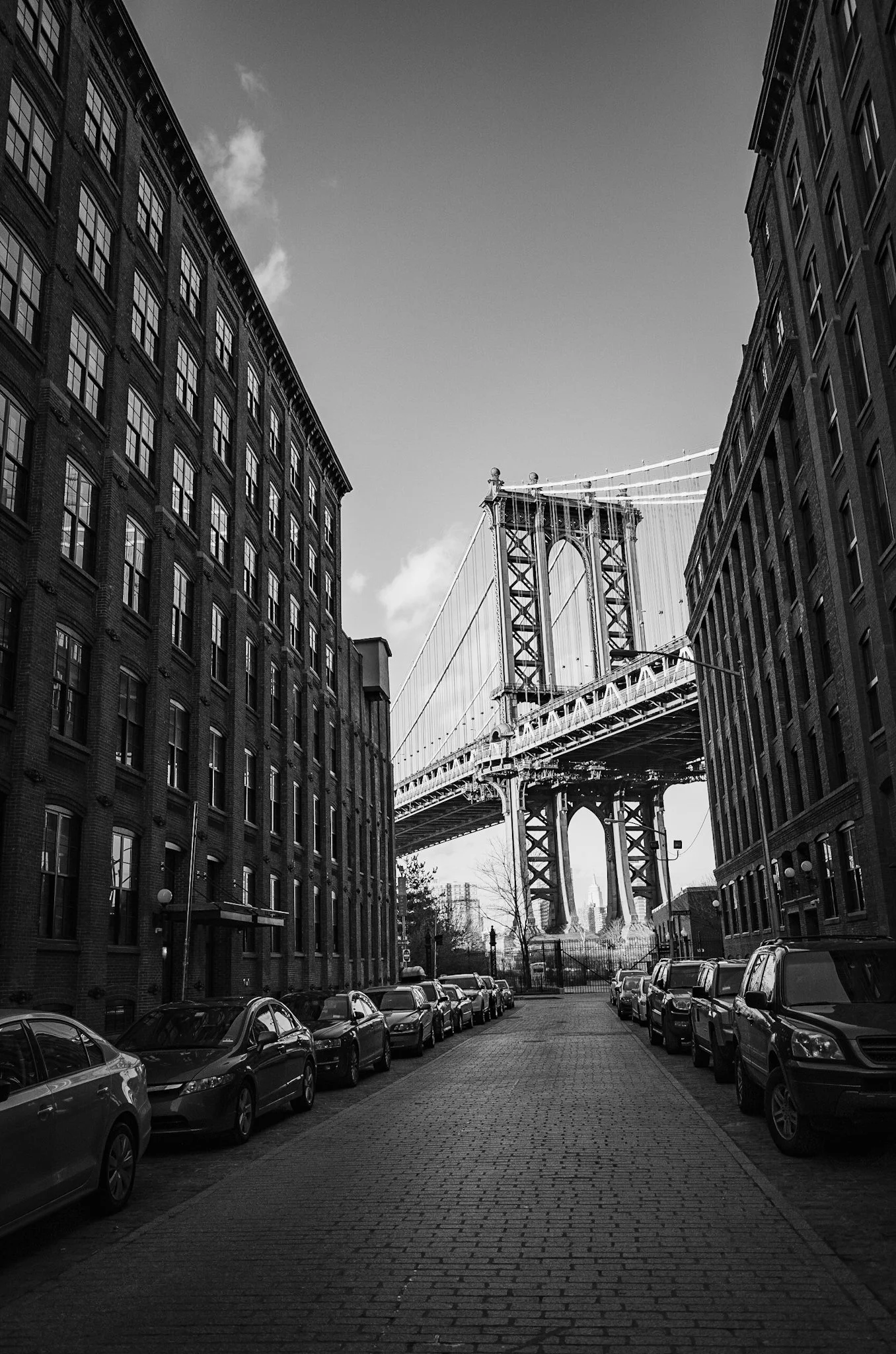 ニューヨークのブルックリンブリッジの橋と周囲の建物を写した黒と白の写真