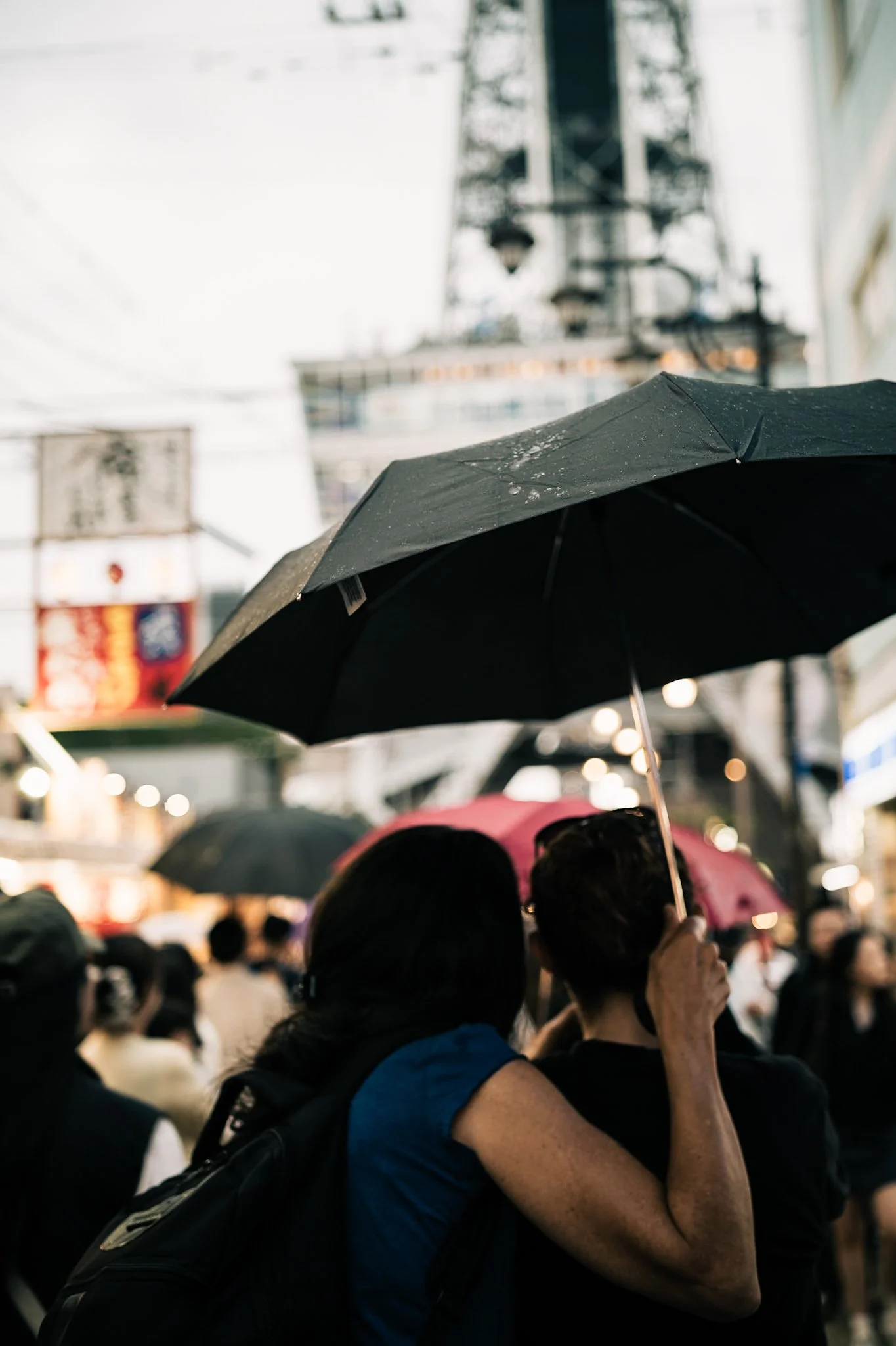 雨の中、多くの人々が傘をさして街を歩いている様子。