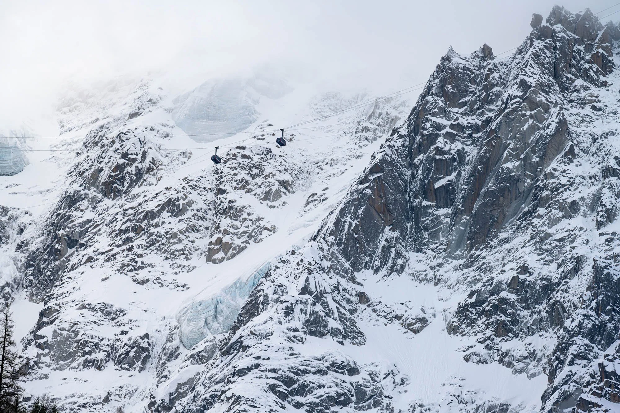Snow-covered mountainous landscape with cable cars traveling across the rugged terrain.