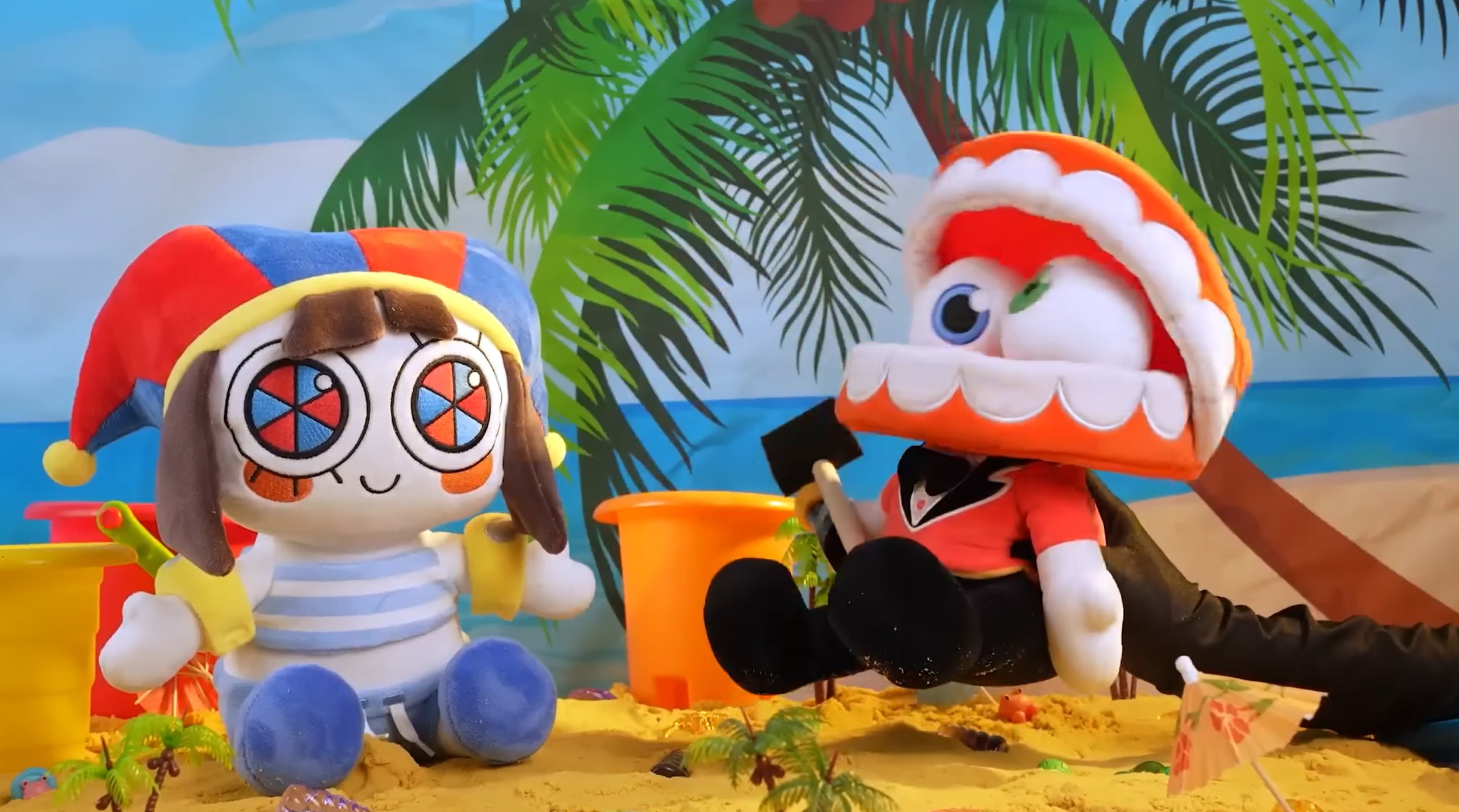 Two plush characters dressed as a pirate and a sailor are sitting on a sandy beach with palm trees, ocean, and painted sky in the background.