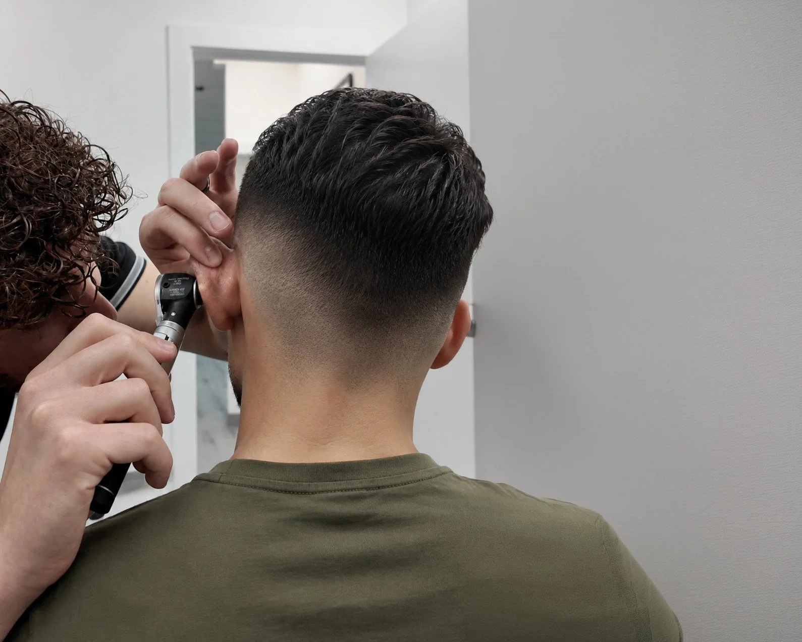 A hearing care technician examining a patients ear.