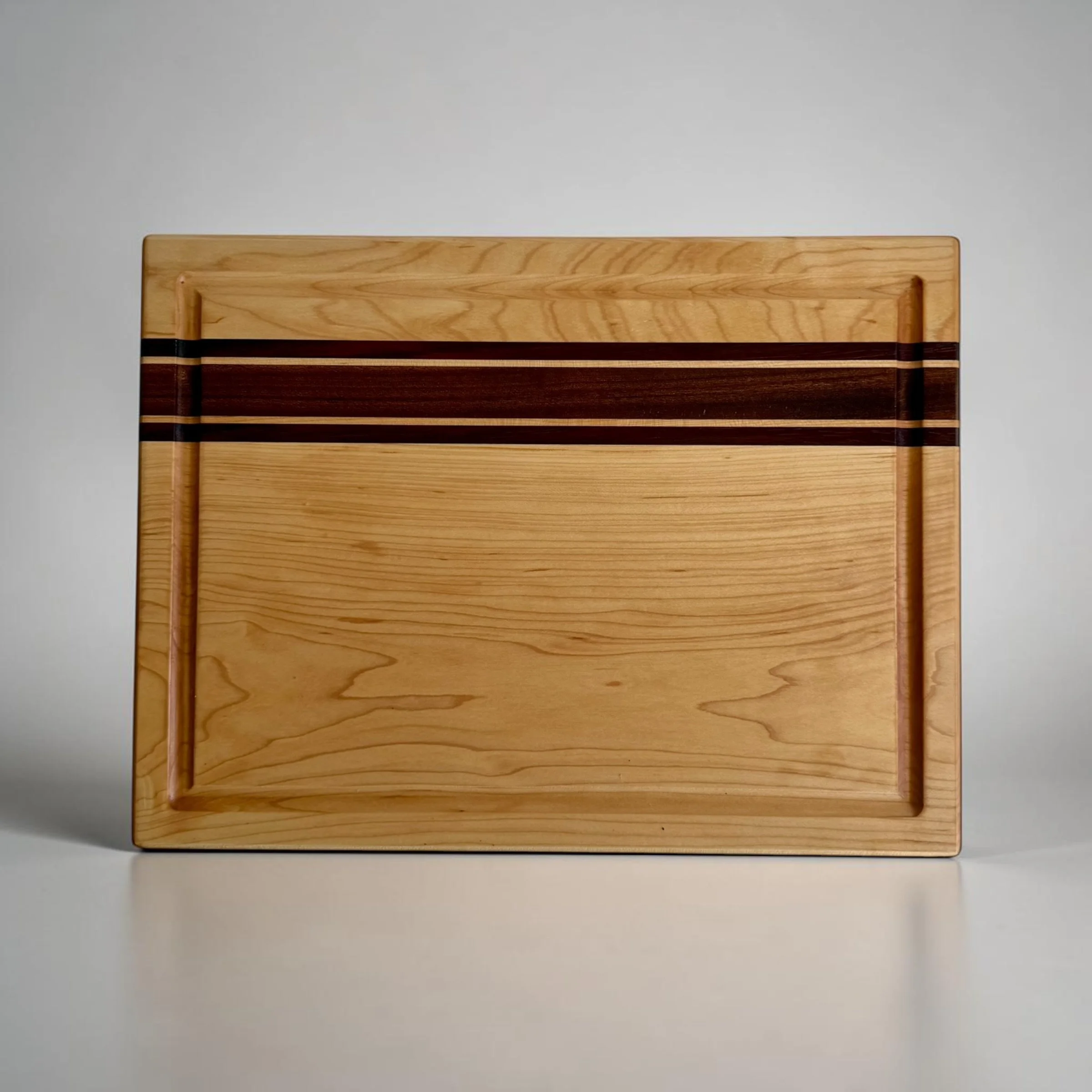 Maple cutting board with sapele and padauk accent stripes and juice groove, top view
