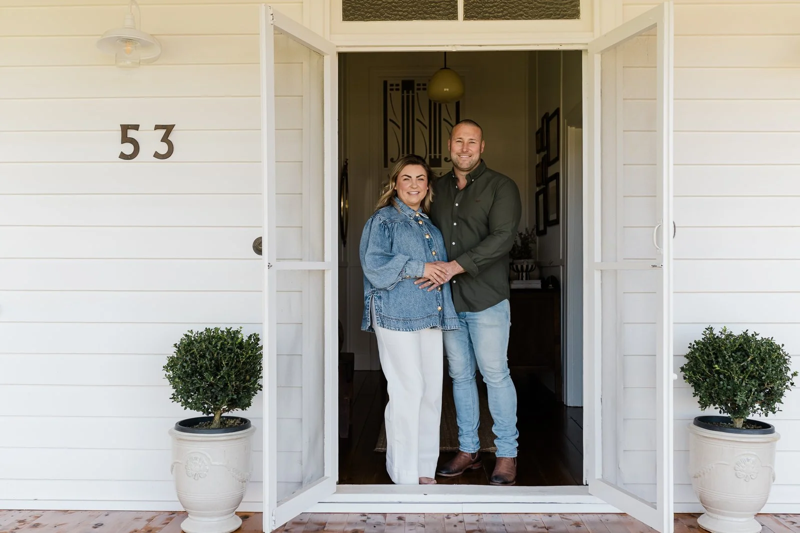 Owners of the property standing at the front door.