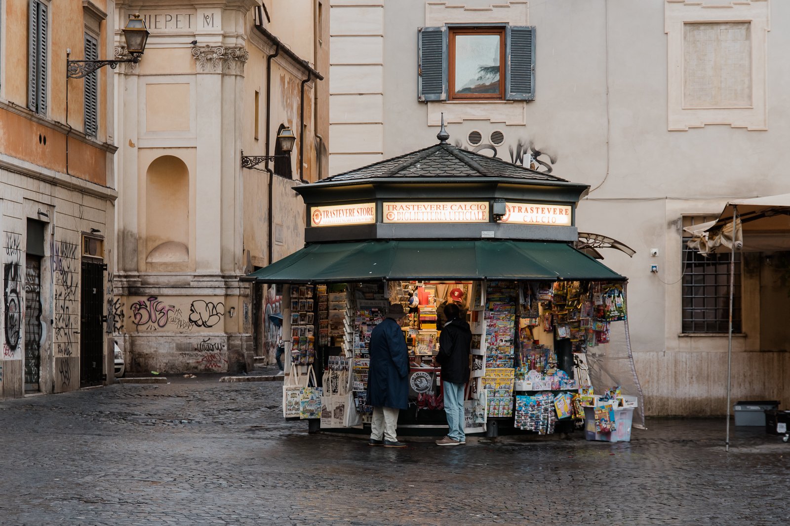 two men buy the daily papers at a kiosk in trastevere